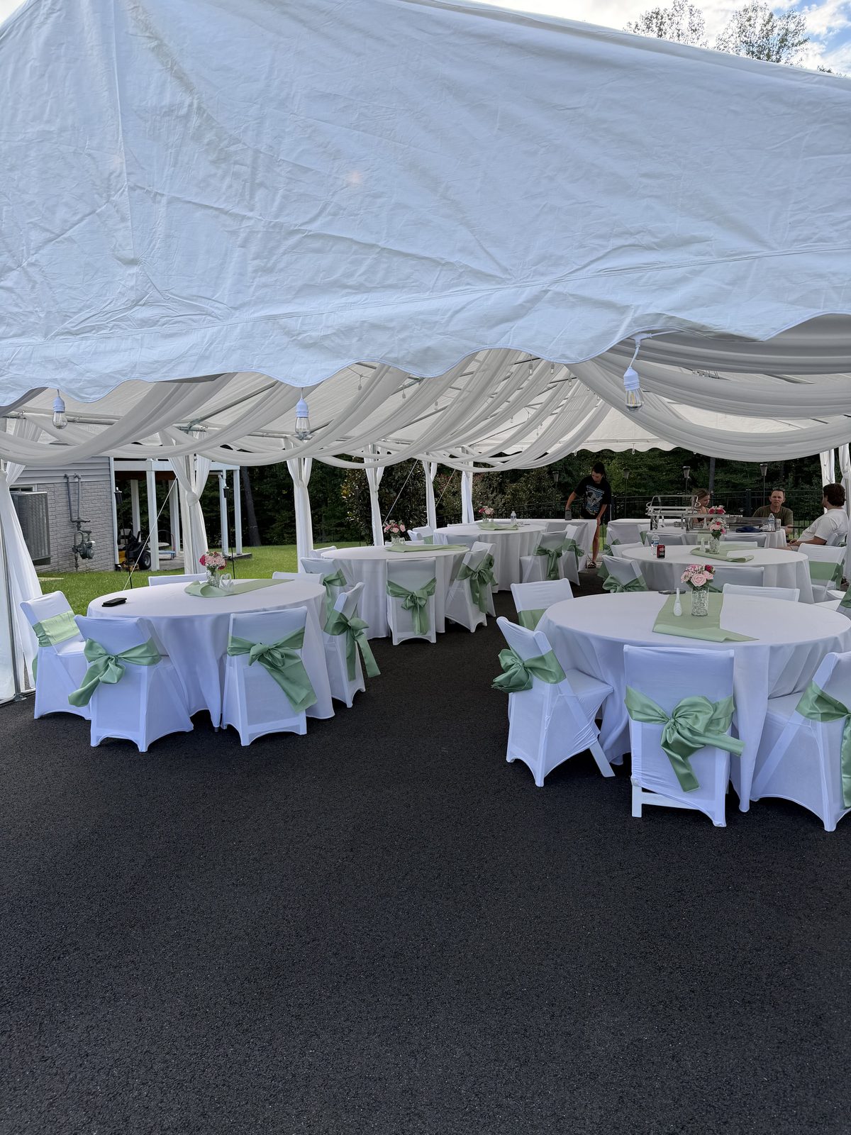 Frame tent with ceiling draping and market lighting over round tables